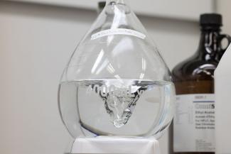 Liquid swirling in a 4000mL beaker with a brown jug of another chemical in the background.